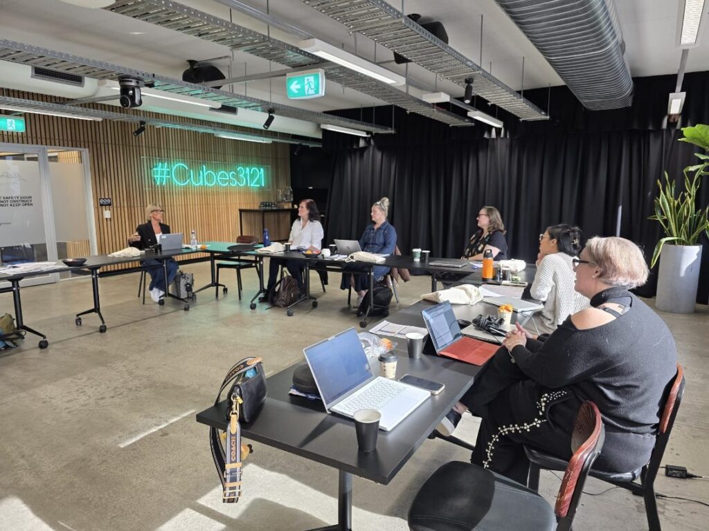 Participants discussing AI with laptops around tables during the chAInge workshop.