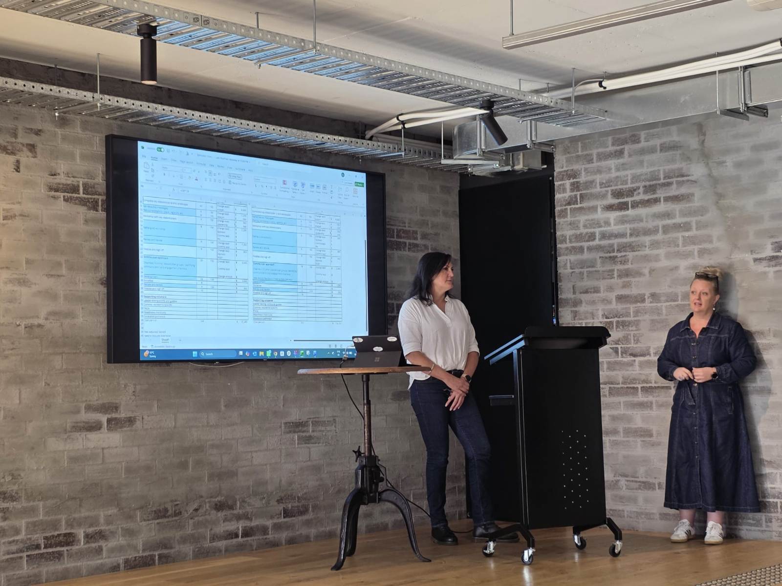 Facilitators presenting beside a projected screen in the chAInge lab